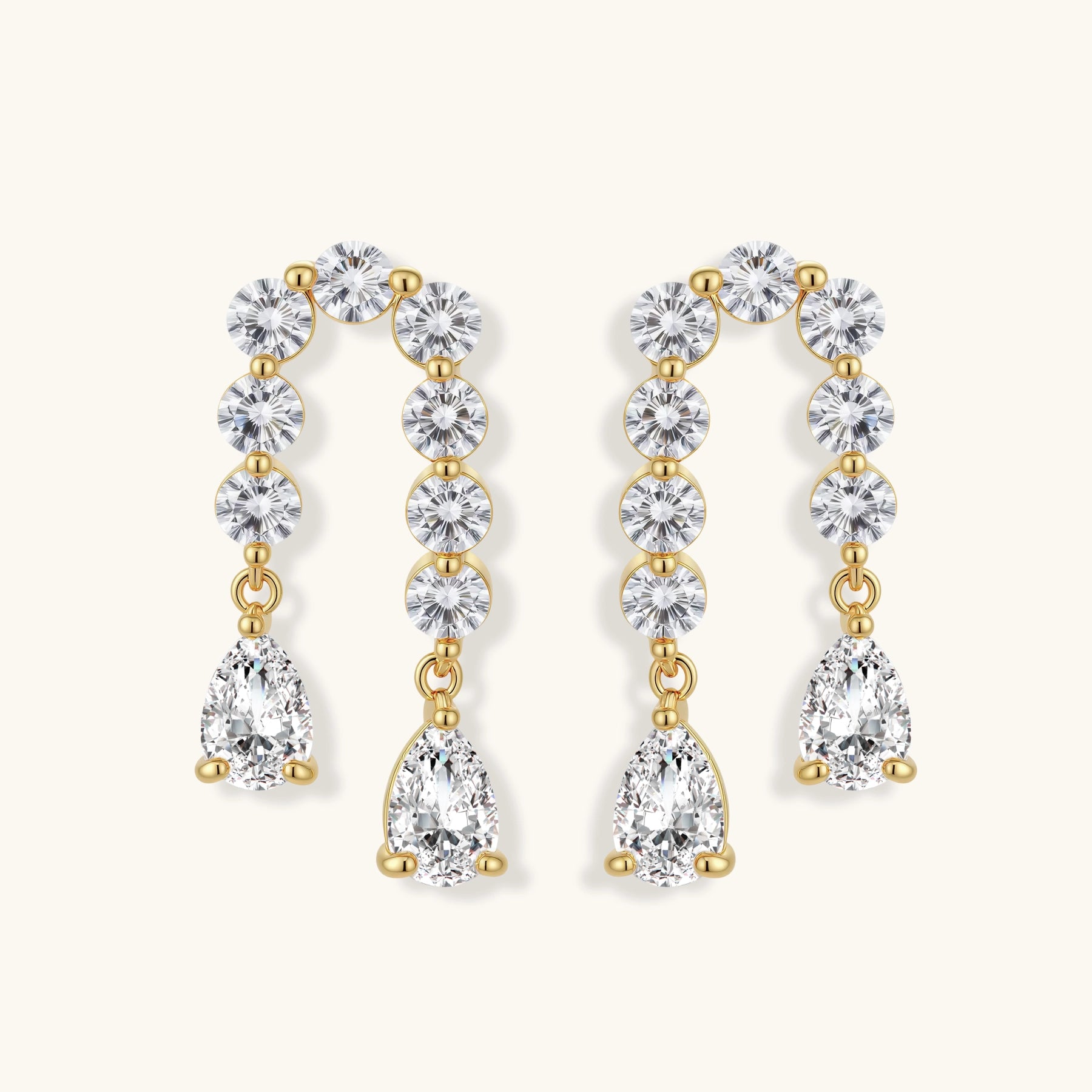 Gold-plated earrings with vertical line of clear crystals and teardrop pendants on neutral background