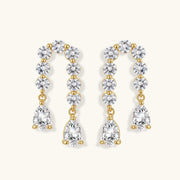 Gold-plated earrings with vertical line of clear crystals and teardrop pendants on neutral background