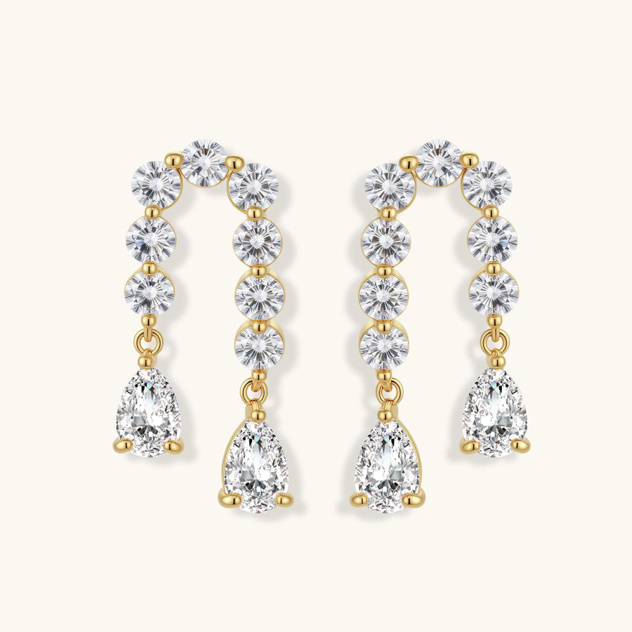 Gold-plated earrings with vertical line of clear crystals and teardrop pendants on neutral background