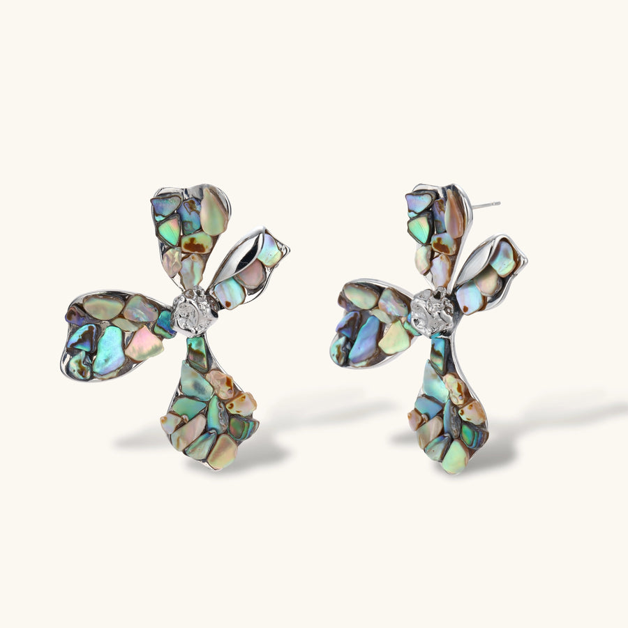 Pair of oversized four-petal flower stud earrings with iridescent teal and blush shell mosaic on silver-tone petals.