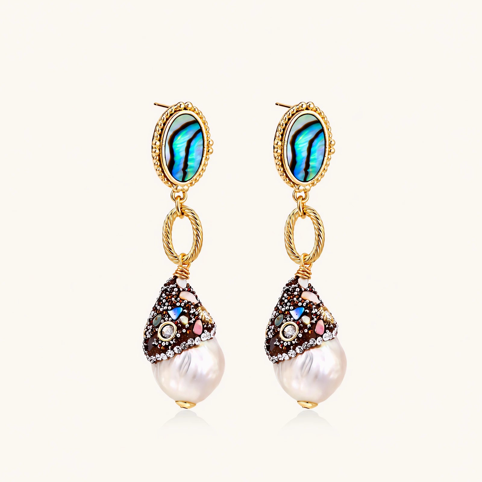 Gold drop earrings with iridescent abalone studs, rope links, jeweled caps and white baroque pearls on cream background