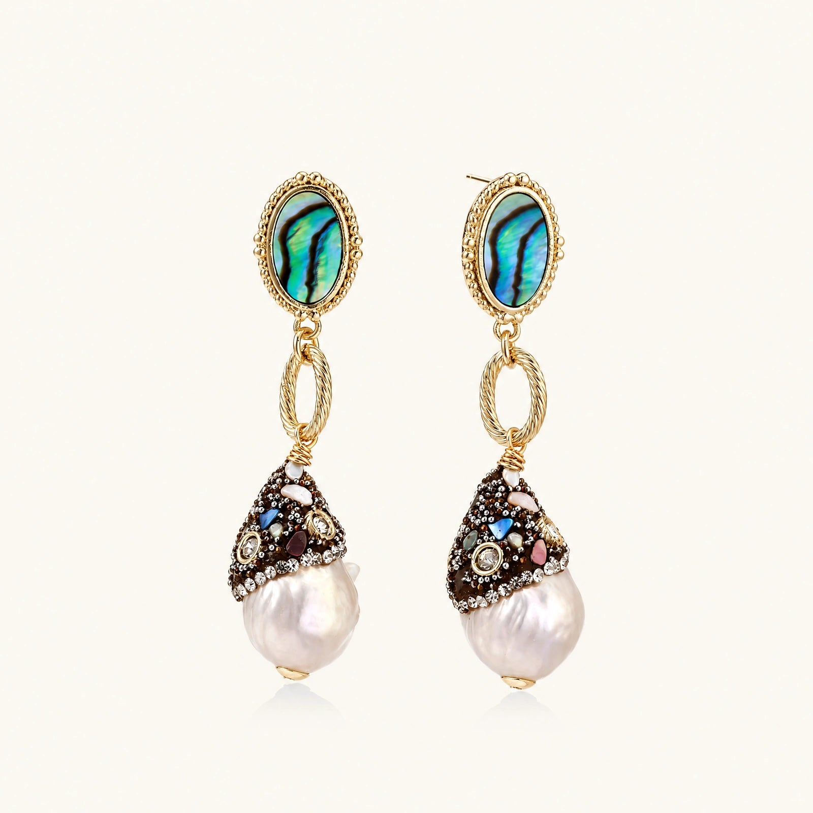 Gold drop earrings with iridescent abalone studs, rope links, jeweled caps and white baroque pearls on cream background