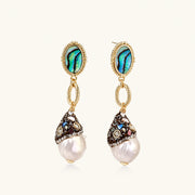 Gold drop earrings with iridescent abalone studs, rope links, jeweled caps and white baroque pearls on cream background