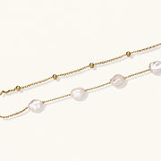 Double-strand gold bracelet with irregular baroque pearls and smooth freshwater pearls on cream background.