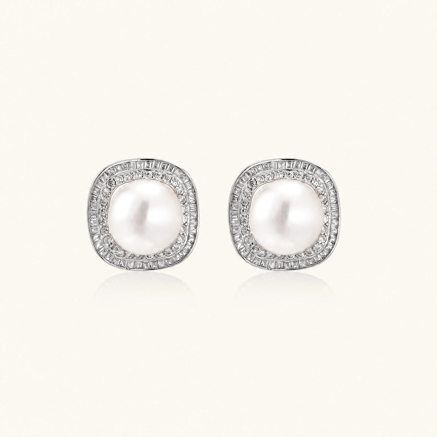Rhodium-plated sterling silver stud earrings with round freshwater pearls surrounded by geometric crystal halos on cream background.