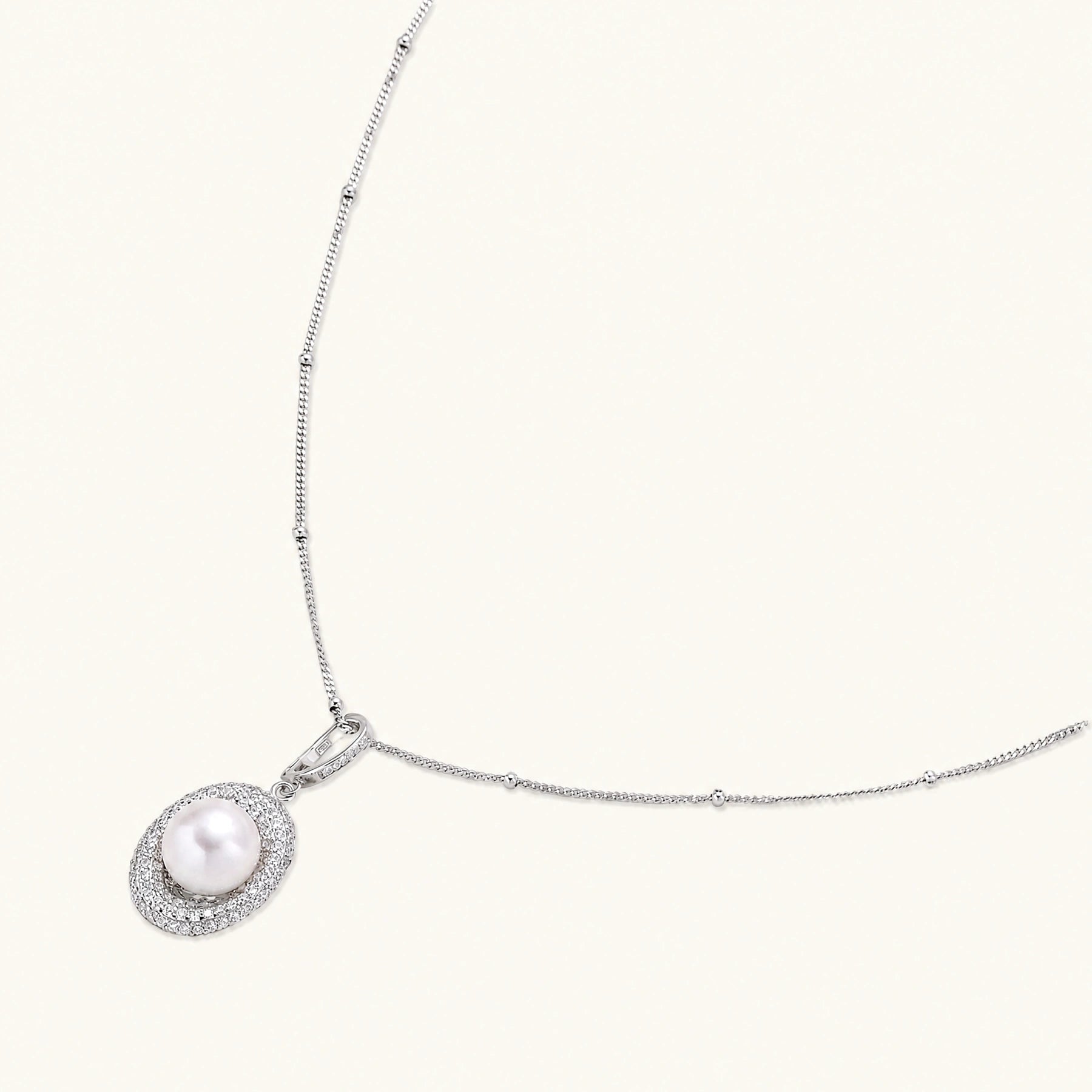 Oval sterling silver pendant with crystal halo surrounding a white freshwater pearl on delicate chain