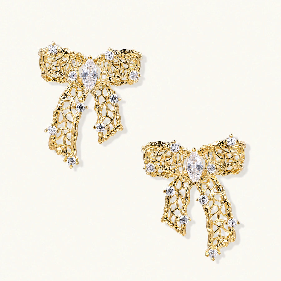Gold-plated bow earrings with openwork design, marquise center stones, and flowing ribbon tails adorned with zirconia crystals.