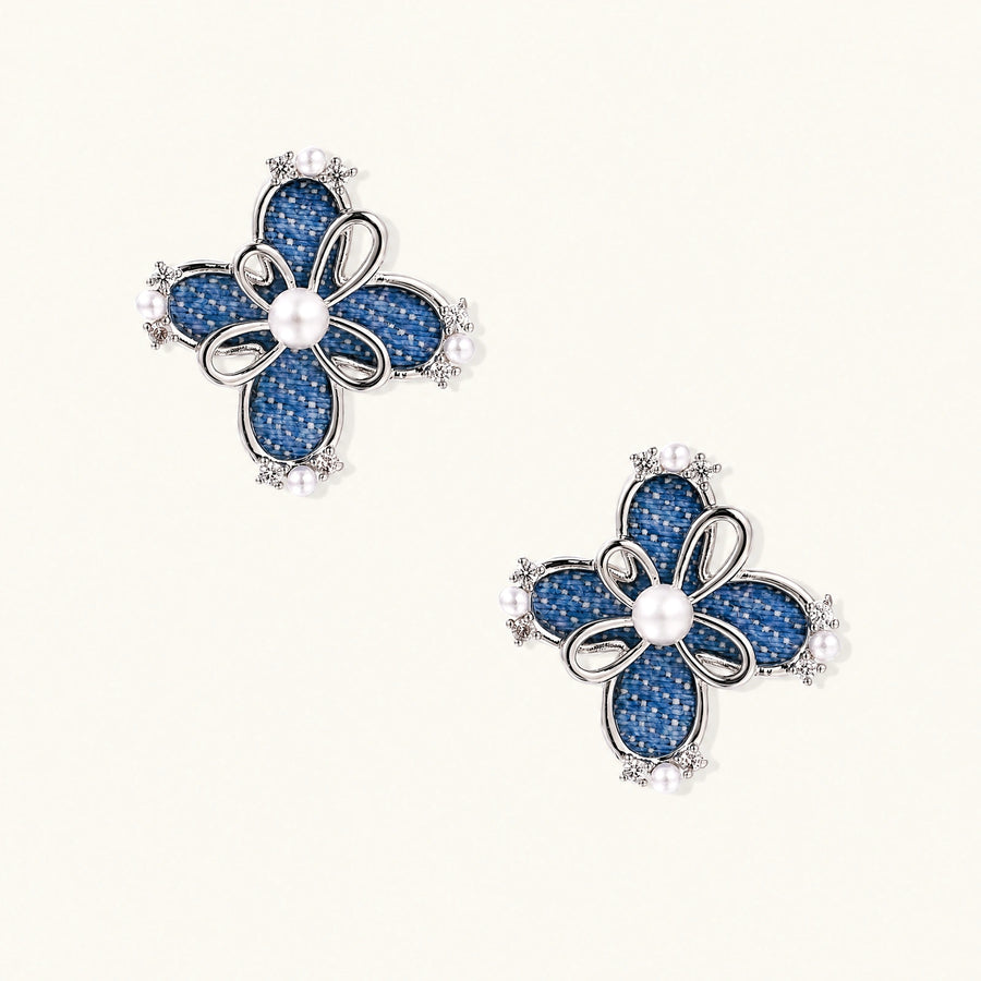 Pair of silver-tone four-petal flower stud earrings with blue denim fabric petals, a center white bead and zirconia accents.