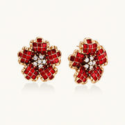 Gold-plated flower studs with burgundy square crystals in petal mosaic and clear center stones on beige background.
