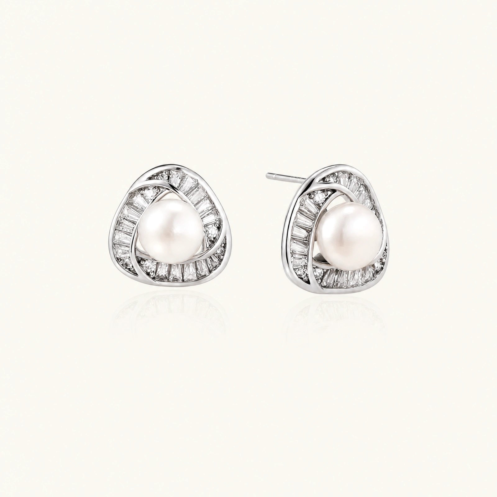 Triangular white gold plated stud earrings with central freshwater pearl and baguette-cut stones on white background