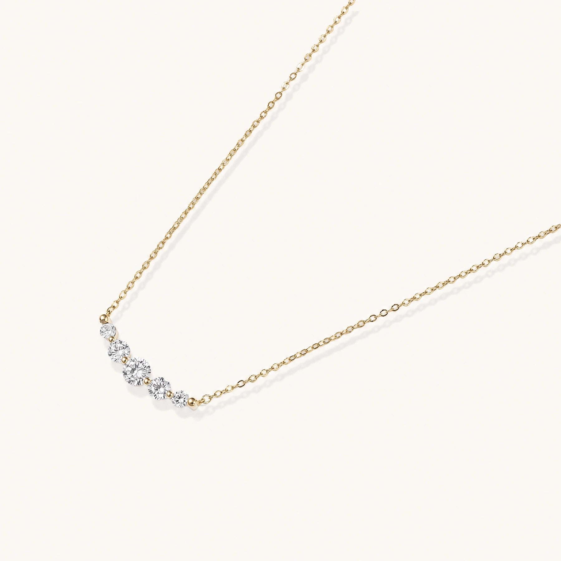 Delicate 14K gold-plated necklace with five graduated zirconia stones arranged in a curved arc on fine chain