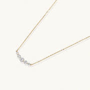 Delicate 14K gold-plated necklace with five graduated zirconia stones arranged in a curved arc on fine chain