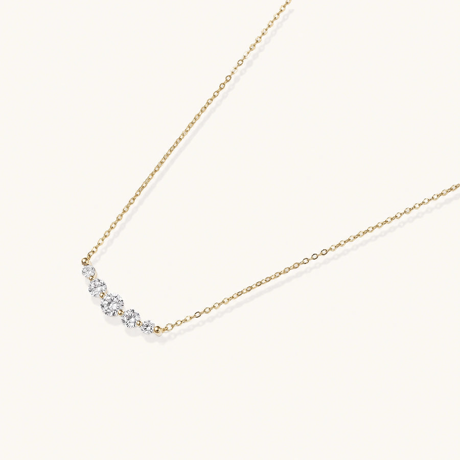 Delicate 14K gold-plated necklace with five graduated zirconia stones arranged in a curved arc on fine chain