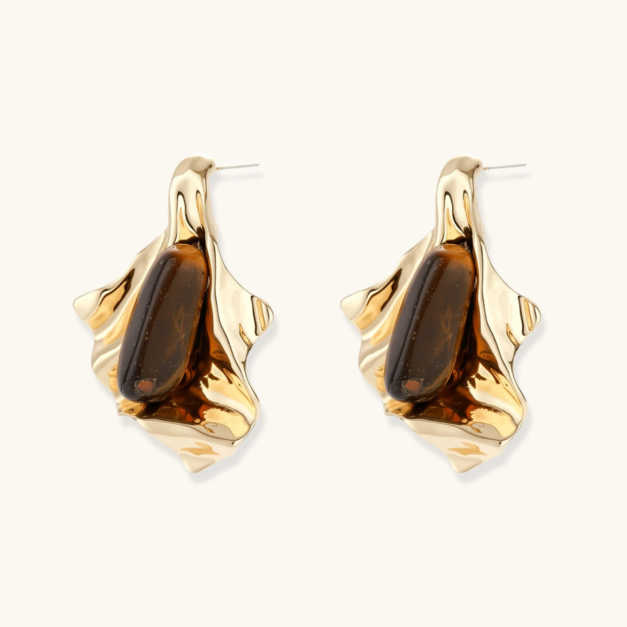 Sculptural gold-tone earrings with flowing organic forms and amber gemstone accents on neutral background