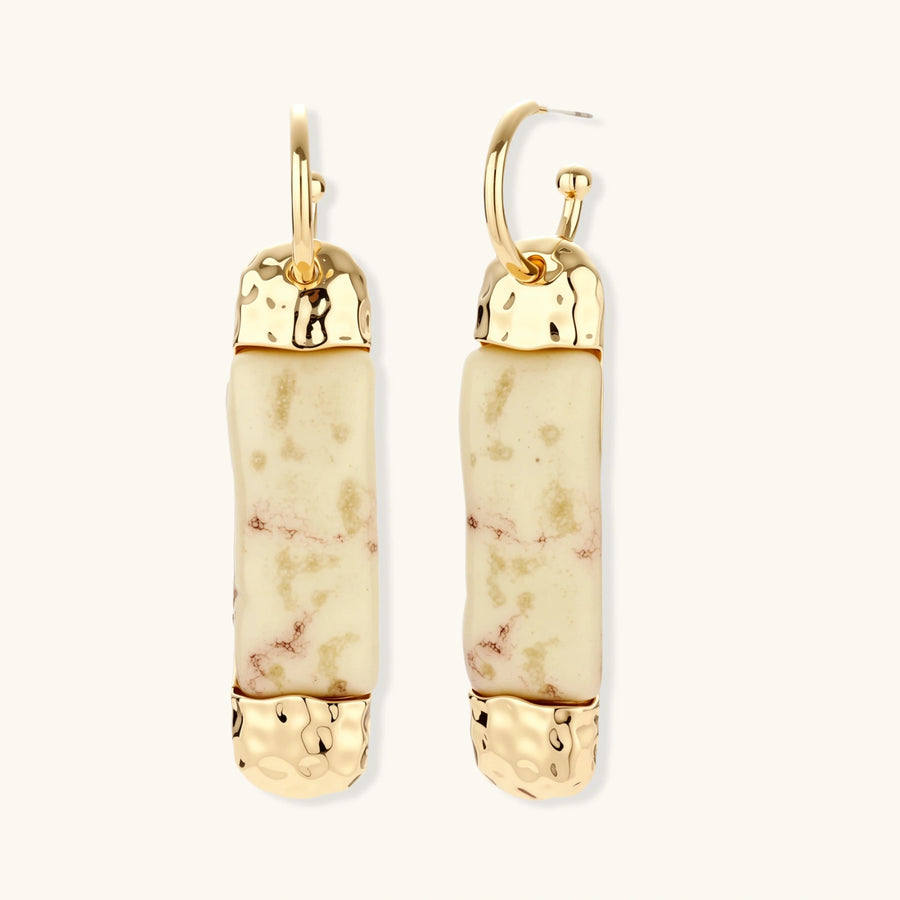 Elongated drop earrings with hammered gold caps and cream marbled resin bars on white background.