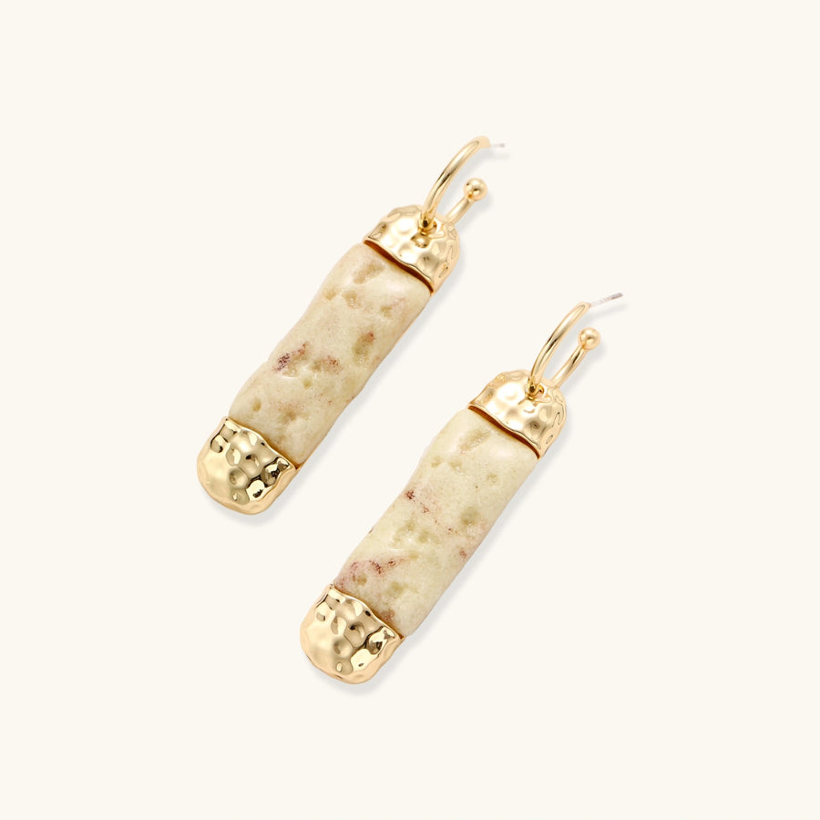 Elongated drop earrings with hammered gold caps and cream marbled resin bars on white background.