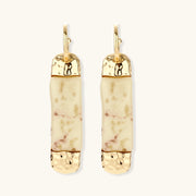 Elongated drop earrings with hammered gold caps and cream marbled resin bars on white background.