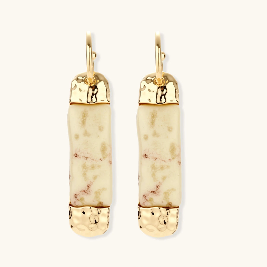 Elongated drop earrings with hammered gold caps and cream marbled resin bars on white background.