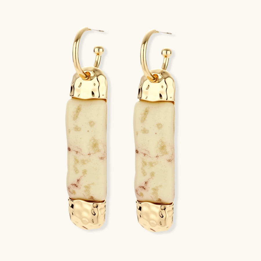 Elongated drop earrings with hammered gold caps and cream marbled resin bars on white background.