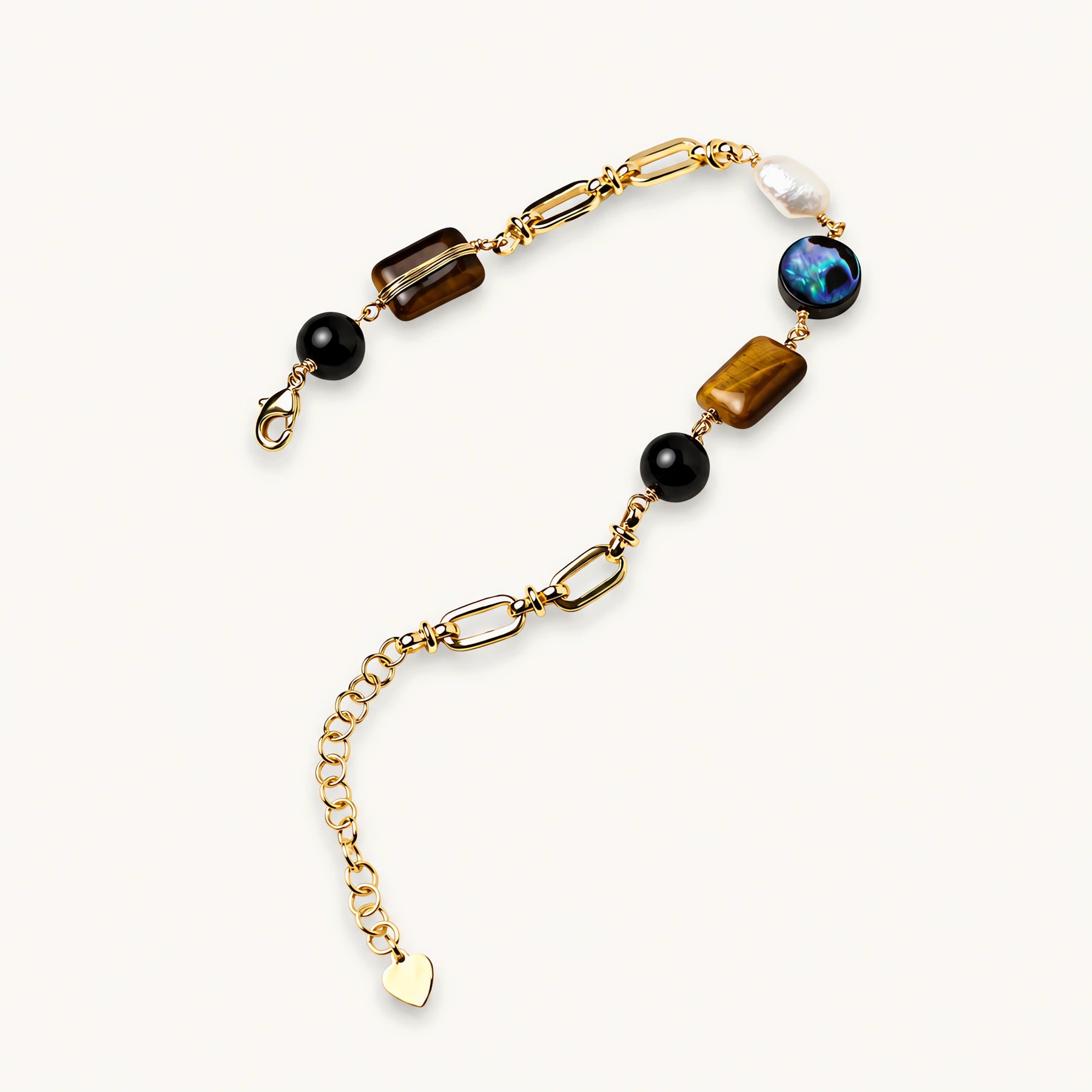 Gold chain bracelet with tiger's eye, obsidian, pearl, and iridescent abalone stones on cream background.