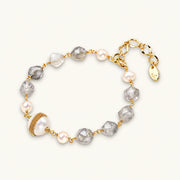 Bracelet with cloudy quartz beads, freshwater pearls, and gold-wrapped baroque pearl centerpiece on white background.