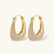 Gold-plated hoop earrings fully covered in sparkling zircon crystals with hinged closure on neutral background