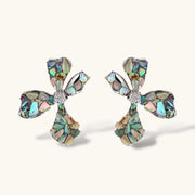 Pair of oversized four-petal flower stud earrings with iridescent teal and blush shell mosaic on silver-tone petals.