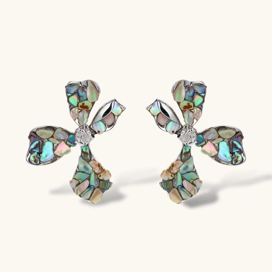 Pair of oversized four-petal flower stud earrings with iridescent teal and blush shell mosaic on silver-tone petals.
