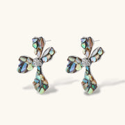 Pair of oversized four-petal flower stud earrings with iridescent teal and blush shell mosaic on silver-tone petals.