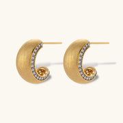Small gold-plated hoop earrings with crystal accents and brushed finish on white background.